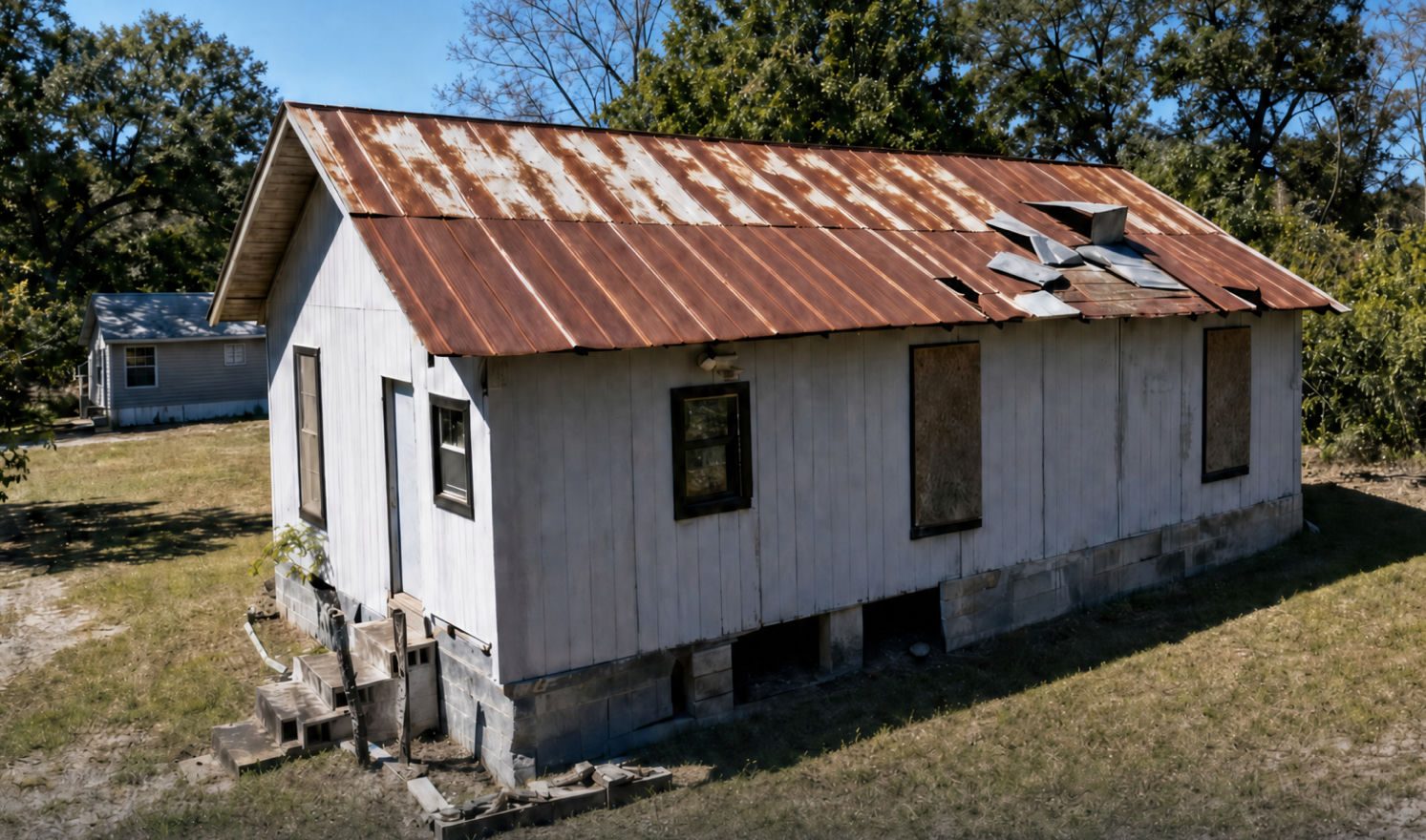 Side view of 231 Jackson Ave showing the metal roof and boarded windows